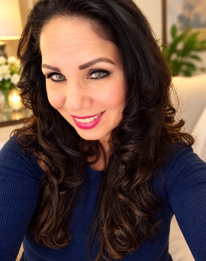 Photo of Cynthia San Miguel smiling, with long dark wavy hair, wearing a navy sweater