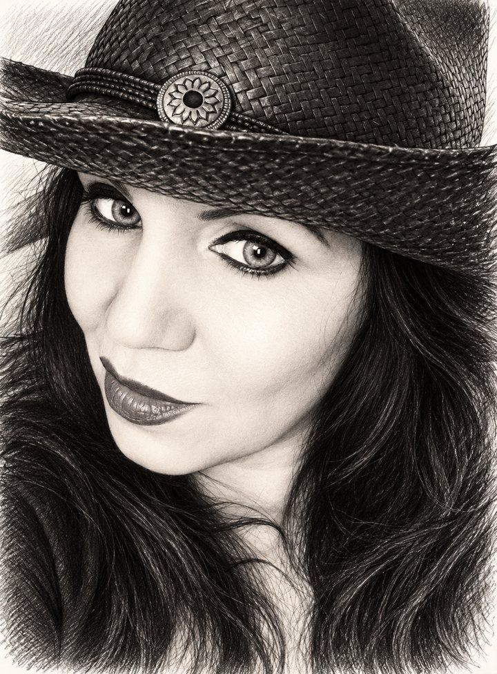 Sepia pencil-style portrait of a woman with long dark hair wearing a woven straw hat with a flower-shaped medallion on the band